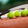 Close up view of tennis racket and balls on the clay tennis court