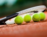 Close up view of tennis racket and balls on the clay tennis court