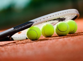 Close up view of tennis racket and balls on the clay tennis court