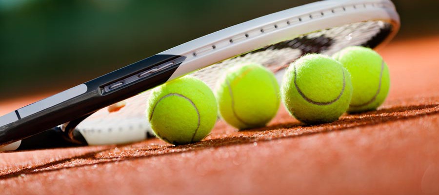 Close up view of tennis racket and balls on the clay tennis court